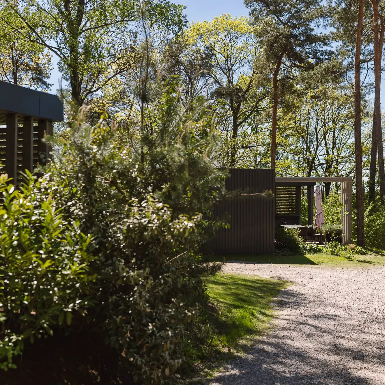 Grindpad tussen groene struiken naar luxe lodges in bosrijke omgeving Markelo