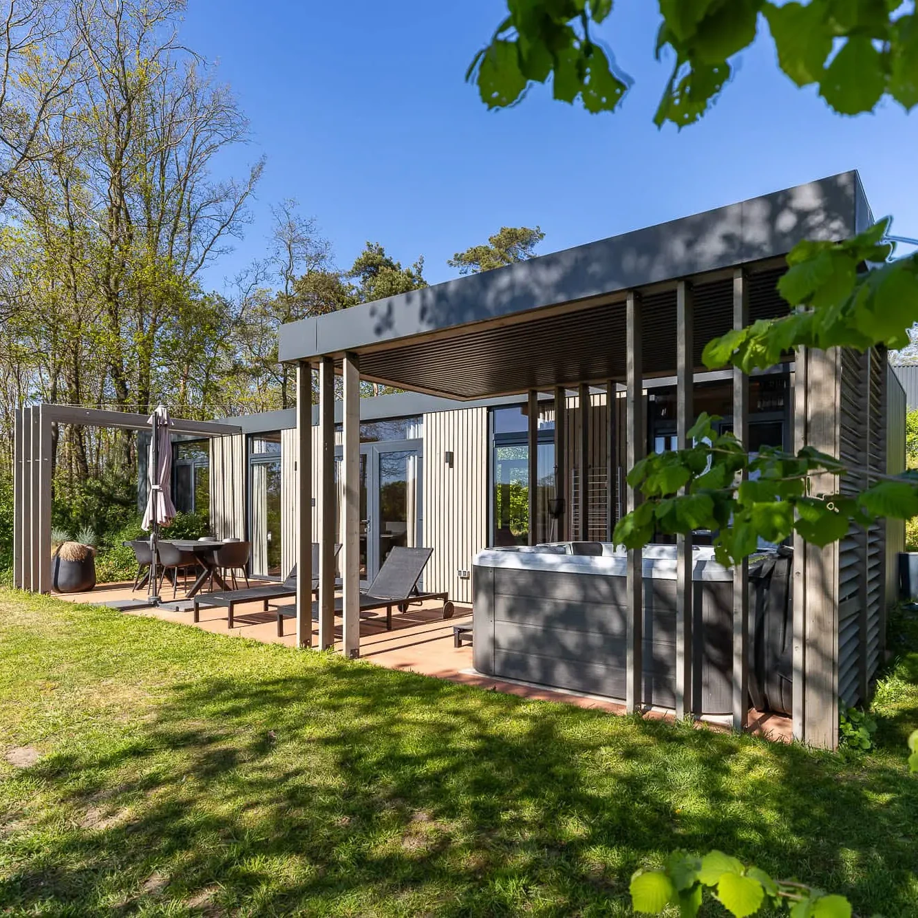 Moderne Panorama lodge met terras, ligbedden en jacuzzi in bosrijke omgeving bij Markelo