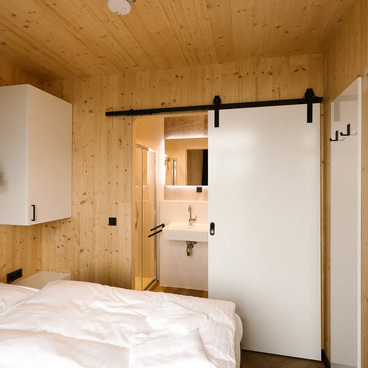 Luxe slaapkamer met houten wanden en plafond, schuifdeur naar badkamer in Panorama lodge Markelo